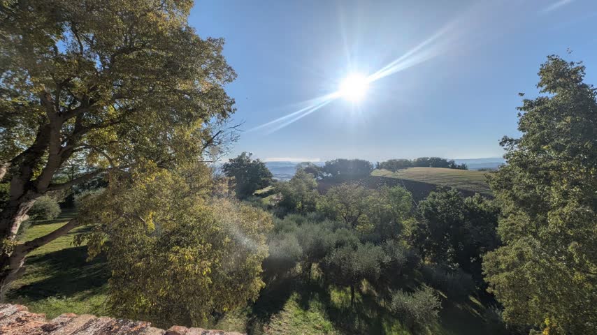 Rural and hilly landscape illuminated by a bright sun in the blue sky