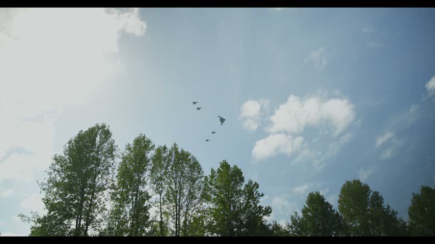 Northrop Grumman b-2 Spirit stealth bomber escorted by 4 Lockheed Martin f-22 Raptor stealth fighters military