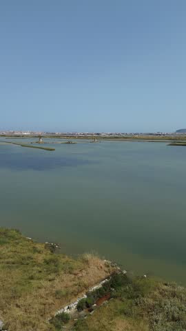 Aerial view of the salt pans and wetlands of Trapani and Paceco in Sicily, featuring geometric evaporation ponds and coastal scenery.