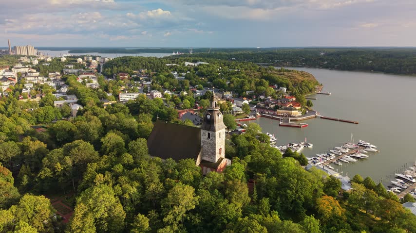 Aerial perspective of the medieval Naantali church nestled in green woods, Finland. Marina and coastal archipelago. Discover the beauty of Naantali church and its adjacent sailing harbor