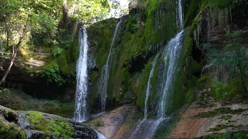 Beautiful natural waterfall cascading over mossy cliff in lush forest