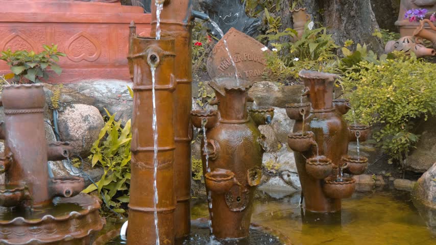 A decorative outdoor water fountains made of cascading terracotta or ceramic pots and bamboo alike columns set in a garden pond area in Po Nagar Temple in Nha Trang, Vietnam. Shot in motion