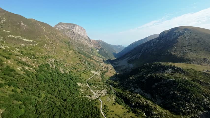 Aerial mountain valley with winding road through green hills