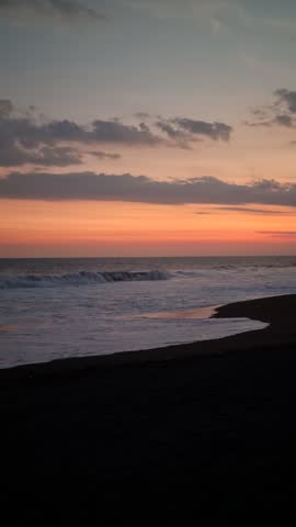 Beautiful sunset over the ocean waves crashing on a sandy beach