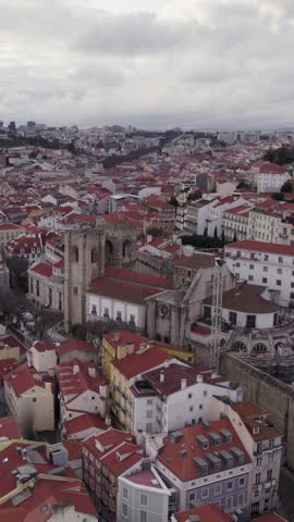 Vertical aerial footage panning across Lisbon Cathedral and the historic old town of Lisbon, Portugal.