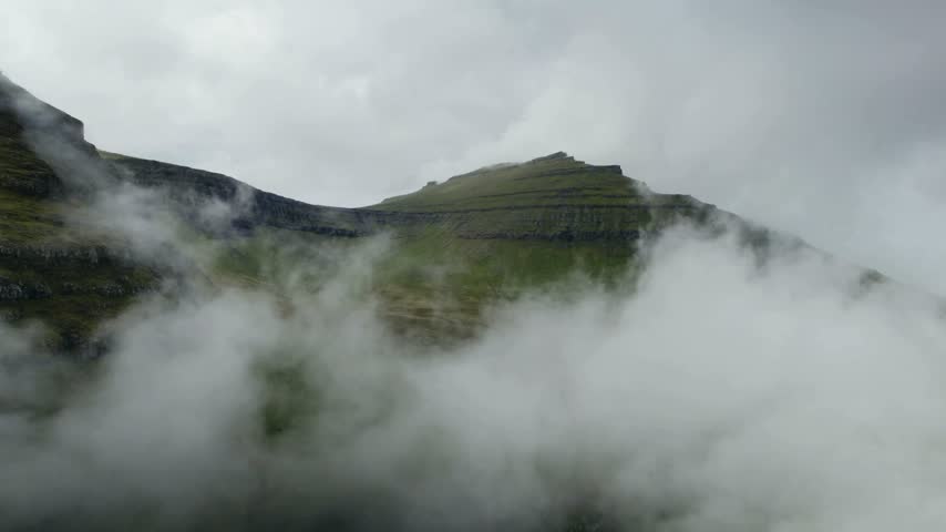 Serene landscape showcases towering mountains partially cloaked in mist, creating a captivating view of nature
