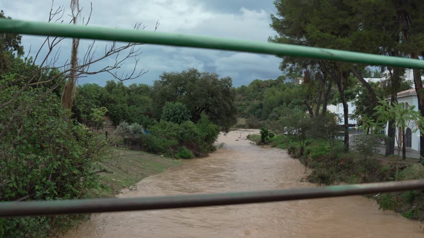 Muddy river water overflowing its banks during a severe weather event and flash flood