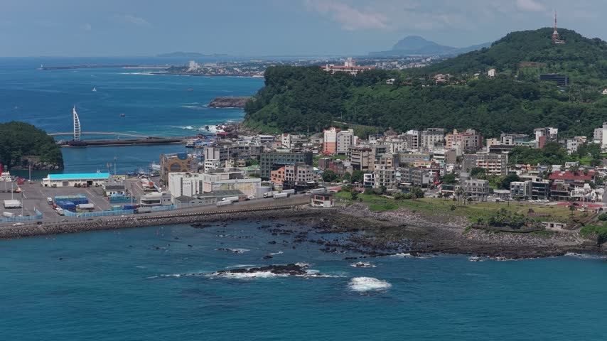 Seogwipo on Jeju Island, South Korea, showing the coastal city landscape and surrounding natural scenery - aerial drone shot