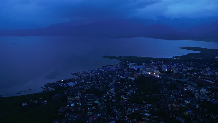 Cinematic aerial view of Buhi town and Lake Buhi during blue hour in Camarines Sur, Philippines. The footage features the urban and lakeside areas around San Benito, San Pascual and Santa Cruz, with M