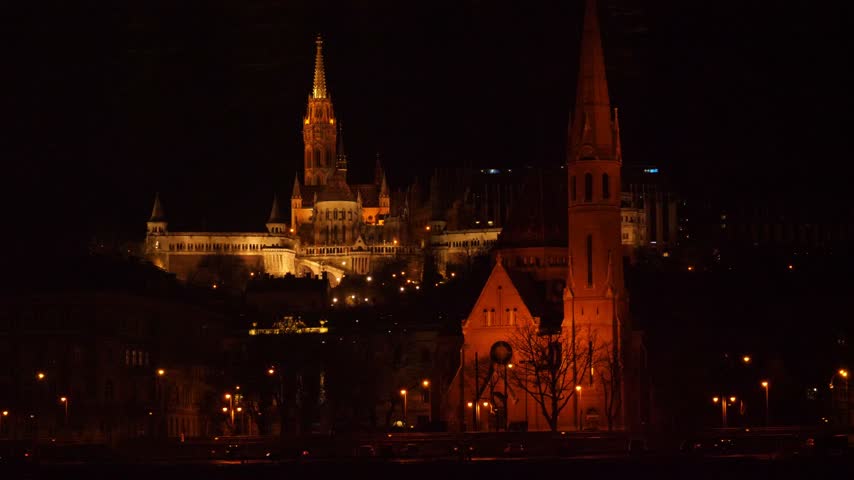 Night view of Matthias Church and the Buda Reformed Church in Budapest, Hungary, beautifully illuminated against the dark skyline of the historic Buda district.