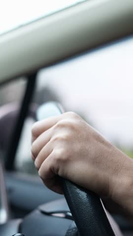 hands gripping the steering wheel while driving car.