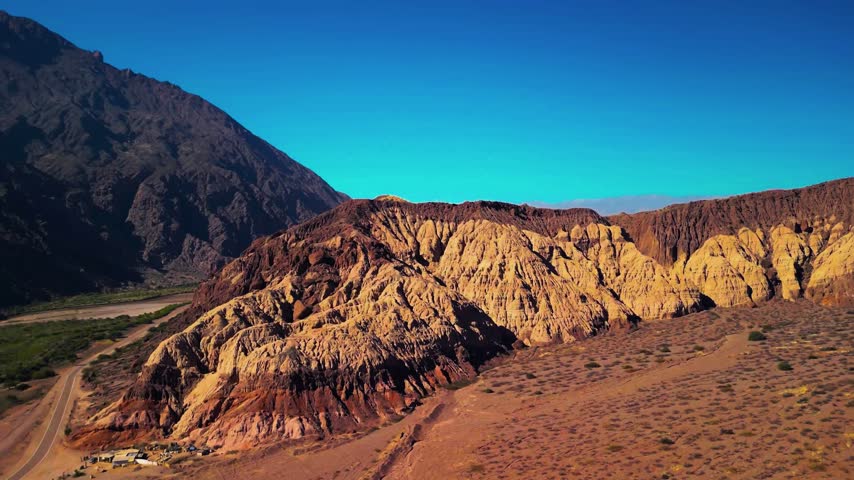 Rugged sandstone ridges and dry terrain stretch alongside a curving mountain road.