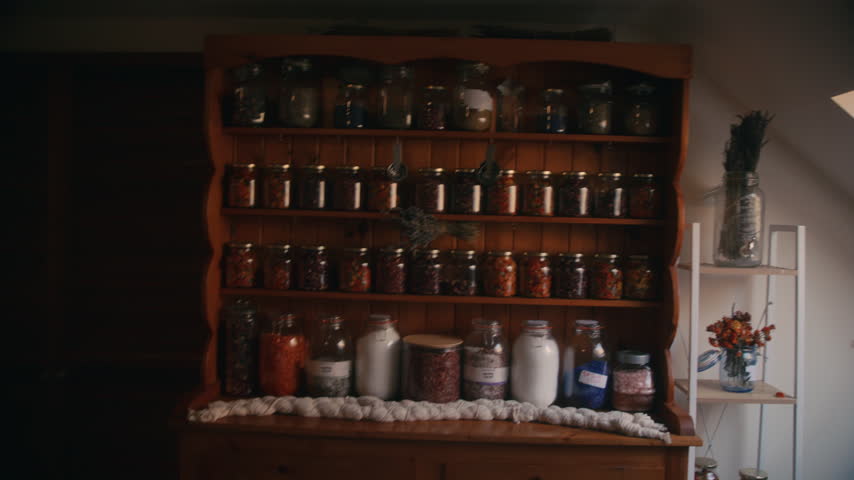 A wide shot of a wooden dresser shelf lined with jars of preserves, bottles, and pantry staples.