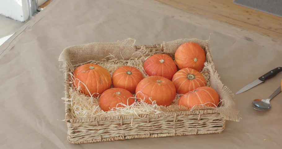 Camera is panning and zooming while tray is staying centered on table, showing halloween pumpkins. Wicker, basket, gourds, burlap, straw, kitchen, workspace