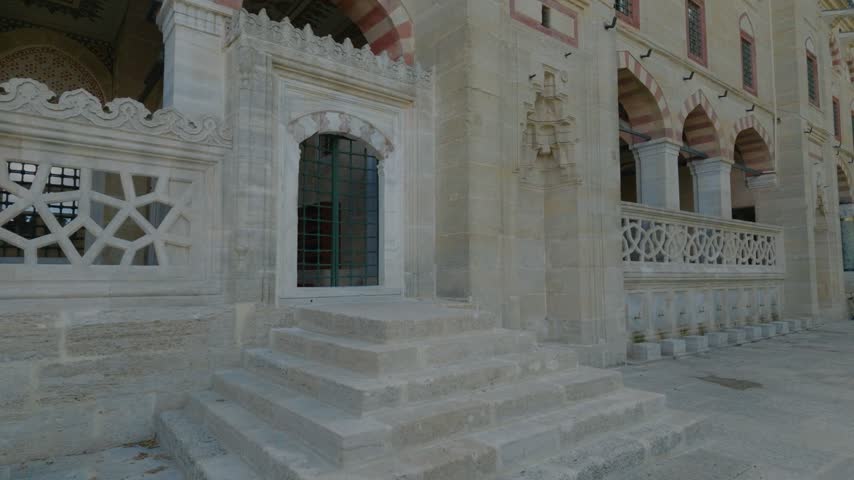 View of the historic Selimiye Mosque featuring intricate stone masonry, arched doorways, and detailed architectural carvings in the courtyard in Edirne Merkez, Edirne, Turkiye.