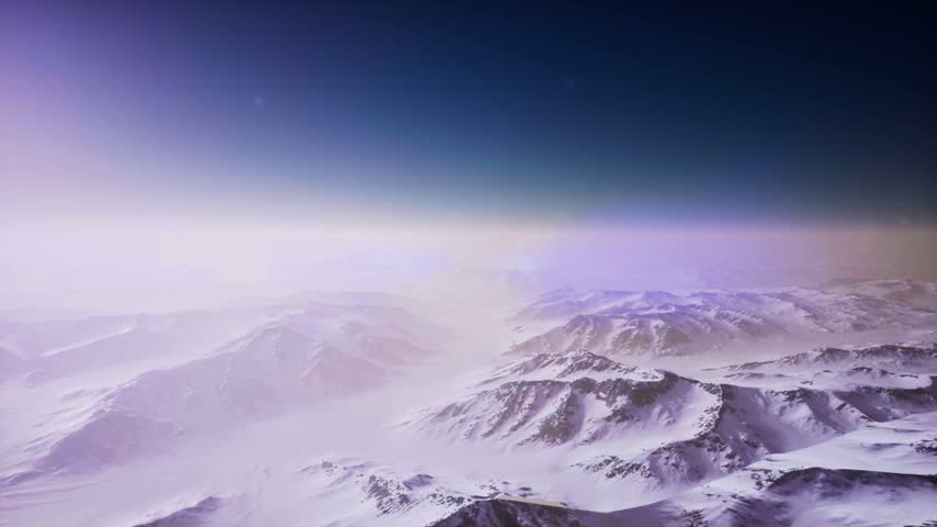 High-altitude peaks and glacial valleys stretch toward a colorful horizon at dusk.