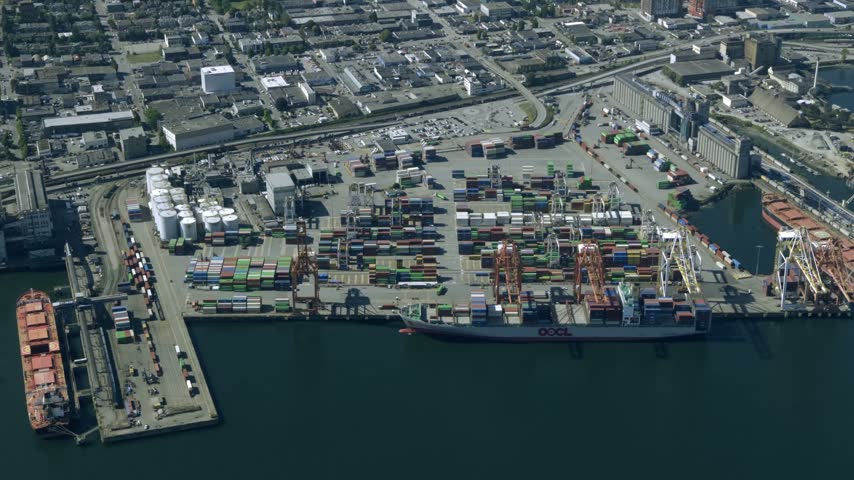 Busy Container Terminal Port With Docked Ships And Stacked Cargo Containers In British Columbia, Canada. Aerial Shot