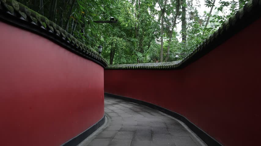 View of the iconic red walls and stone path at Wuhou Temple surrounded by lush greenery in Chengdu, Sichuan, China.