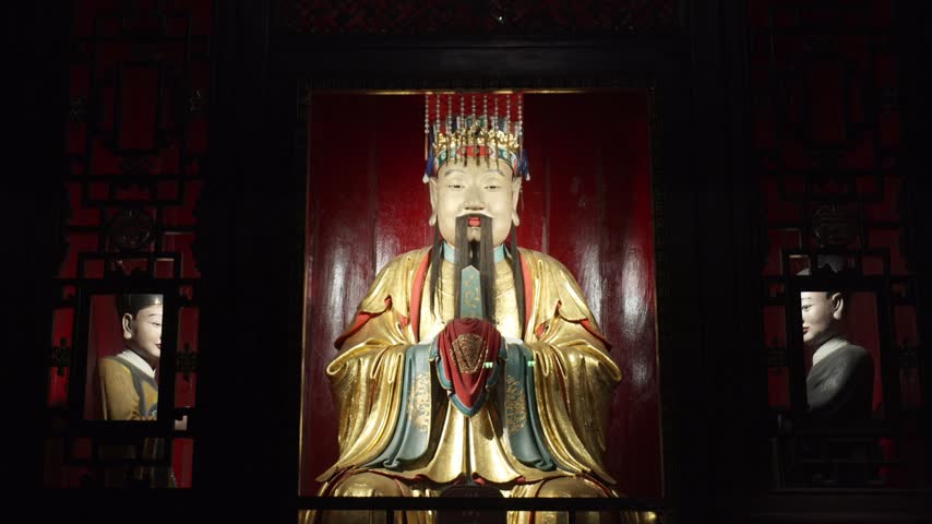 View of the golden statue of Liu Bei at Wuhou Temple, featuring intricate traditional attire and an ornate crown, set against a deep red background in Chengdu, Sichuan, China.