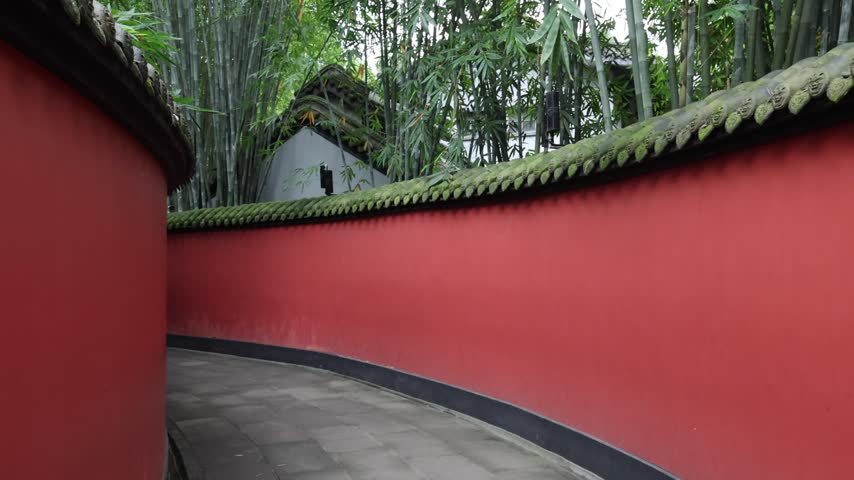 View of the iconic red wall at Wuhou Temple surrounded by lush bamboo groves in Chengdu, Sichuan, China.