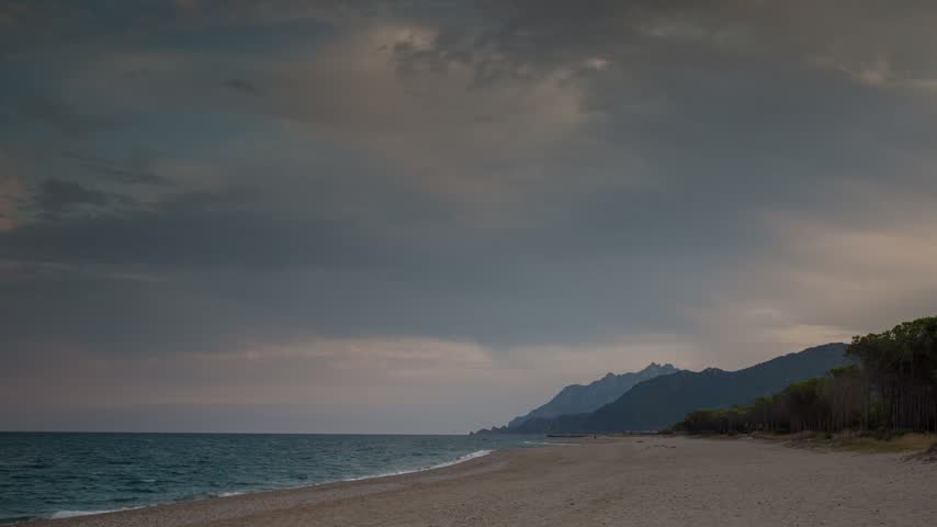 Serene Dusk Beach with Mountain Range and Cloudy Twilight Sky