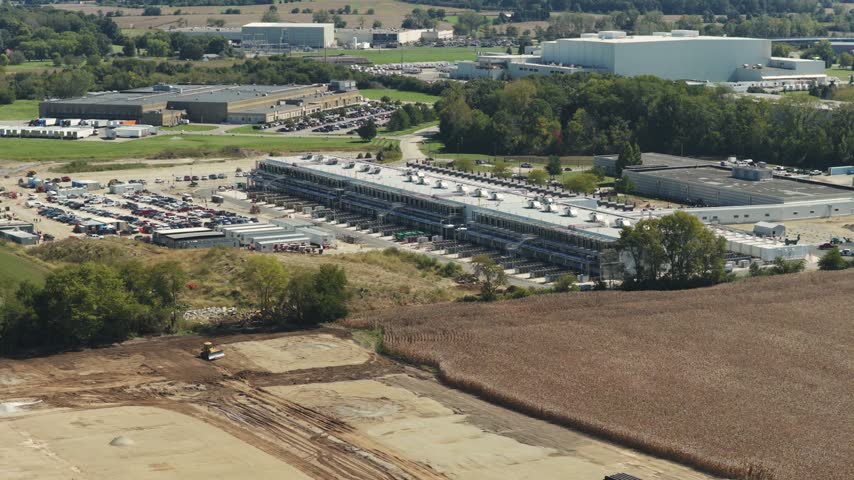 Drone aerial establishing view of large white data center construction being built in central Ohio by Springfield, OH near countryside rural country landscape of tech data building for AI hardware 4k
