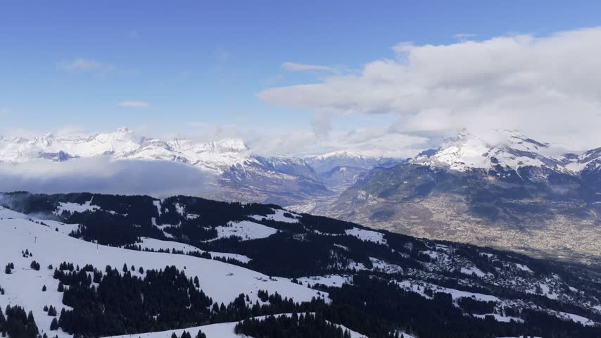 Wide panoramic aerial view of the snow-covered Alps in winter, showing the valleys and mountains around Sallanches, Passy, and the Mont Blanc massif in the French Alps. The landscape features dramatic