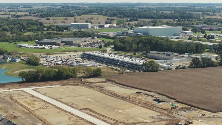 Drone aerial establishing view of large white data center construction being built in central Ohio by Springfield, OH near countryside rural country landscape of tech data building for AI hardware 4k