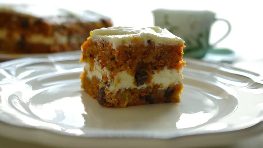 Slice of Homemade Carrot Cake with Cream Cheese Frosting on a White Plate