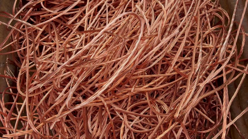 Zooming into a pile of bright copper wire scrap recovered from power cables, recycled copper for remelt
