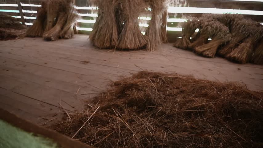 Rustic wooden barn interior with bundled dried grass and traditional agricultural storage.