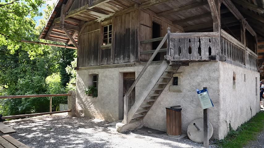 Rustic historic timber farmhouse with balcony and weathered wooden facade in the Swiss countryside.