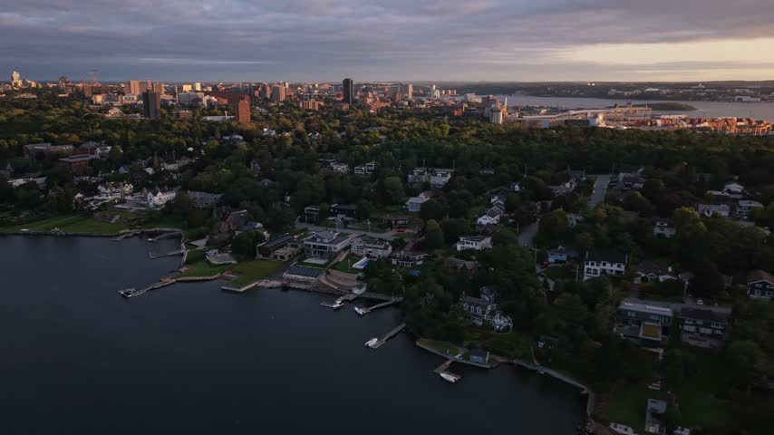 A stunning aerial view captures Halifax, Canada, transitioning from day to night. The vibrant city showcases lush greenery and serene waterfronts as the sky darkens.