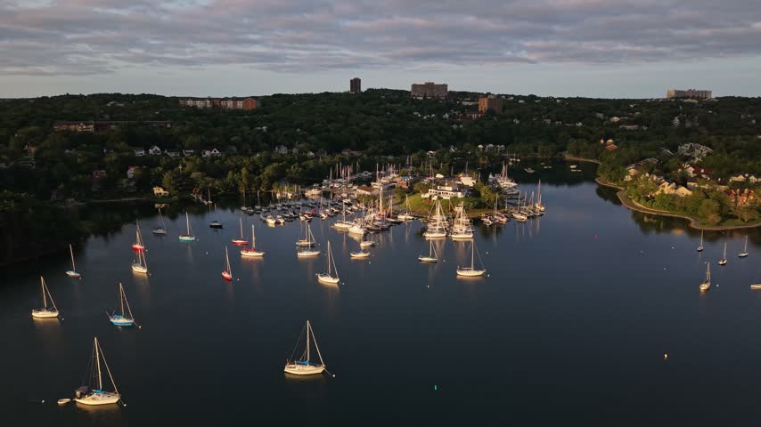 Experience the stunning aerial perspective of Halifax, Canada, with serene waters dotted by sailing boats, lush greenery, and a lively marina atmosphere.