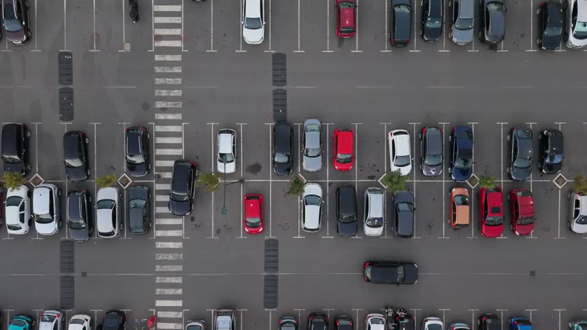 Several cars are parked in a large parking lot. The layout shows marked spaces and a crosswalk.