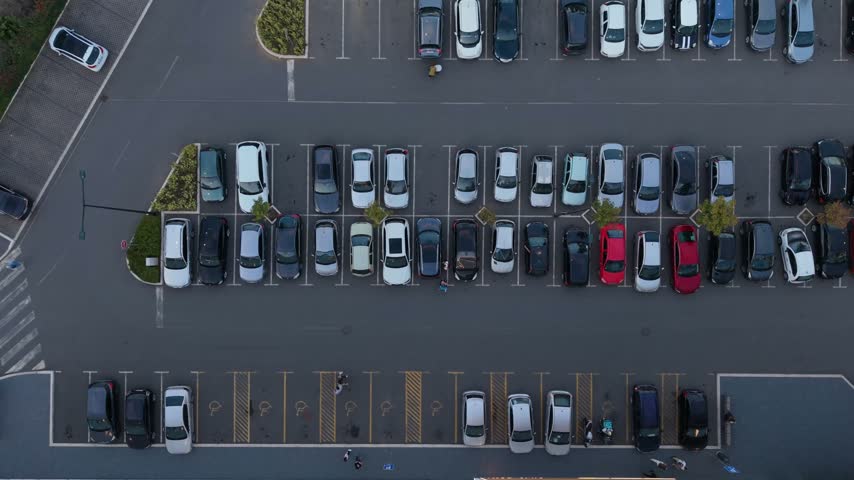 Aerial view of a busy parking lot filled with cars parked in rows during the day.
