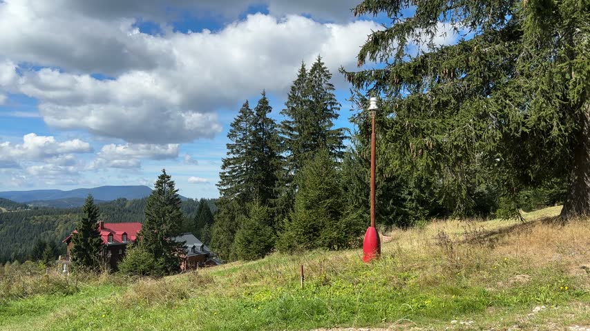 Scenic view of the Beskids mountain landscape with green meadows, forested hills, countryside and distant mountains under a partly cloudy sky.