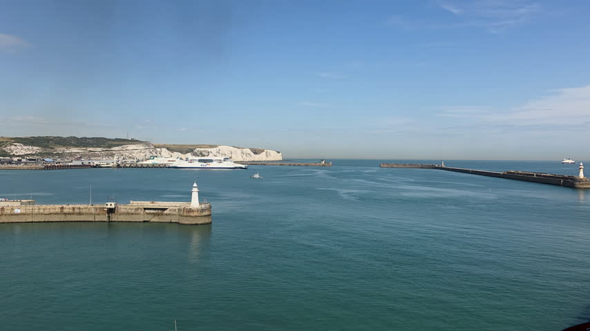 Dover Harbour entrance in Dover, Kent, England, United Kingdom, with Prince of Wales Pier lighthouse, White Cliffs of Dover, English Channel and harbour breakwaters, static
