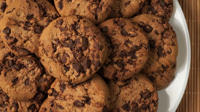 Close-up dolly shot of delicious homemade chocolate chip cookies stacked on a white plate