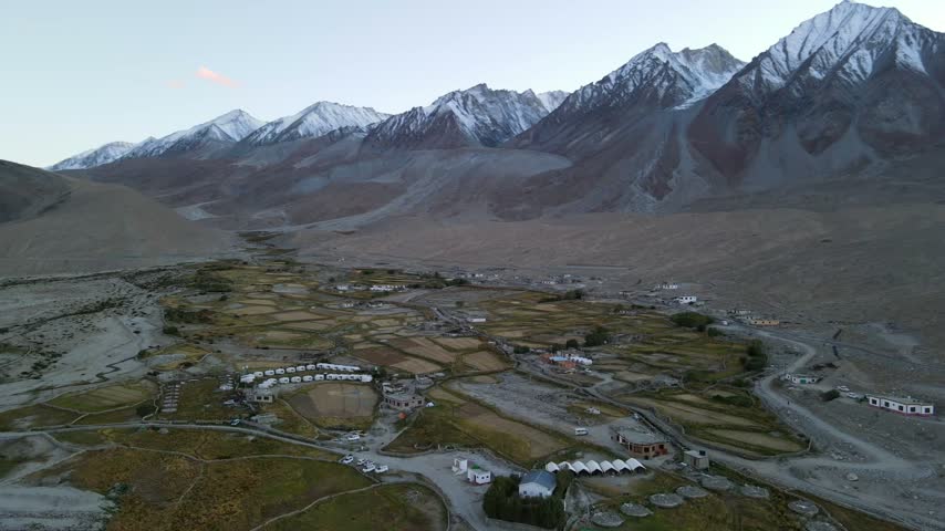 Stunning aerial view of mountain valley village surrounded by snow capped peaks near Pangong Tso in Ladakh