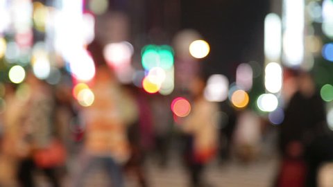 People walking in city night background. Pedestrians walking in city night with lights. Out of focus background from busy big city with people crossing street. Tokyo, Japan.