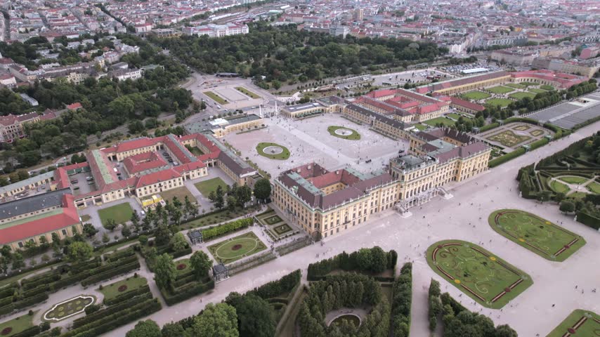4K drone aerial view of a historic palace and surrounding cityscape in Vienna, Austria. Ornate architecture, landscaped grounds and dense urban buildings create a distinctive European scene.