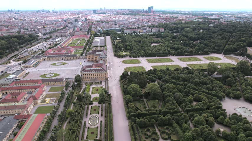 4K drone aerial view of a historic palace and surrounding cityscape in Vienna, Austria. Ornate architecture, landscaped grounds and dense urban buildings create a distinctive European scene.