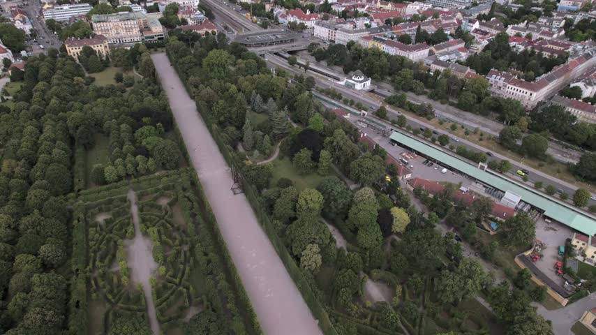 4K drone aerial view of a historic palace and surrounding cityscape in Vienna, Austria. Ornate architecture, landscaped grounds and dense urban buildings create a distinctive European scene.