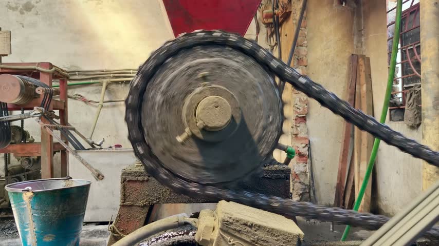 Close up of a large heavy-duty gear and chain mechanism rotating rapidly during industrial production inside a workshop
