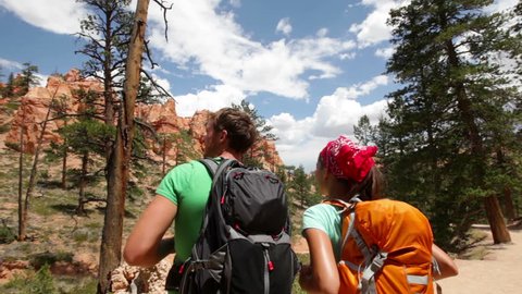 People hiking - couple hikers in Bryce Canyon walking smiling happy together. Multiracial couple, young Asian women and Caucasian men in Bryce Canyon National Park landscape, Utah, United States.