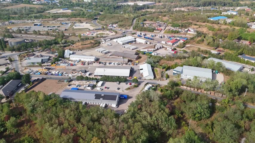 Tatabánya, Hungary industrial park with factories, warehouses, trucks and transport infrastructure in a commercial zone, viewed from an aerial perspective.