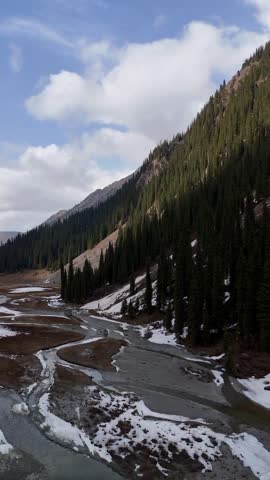 Peaceful wilderness scenery captured from above, showing a lake, river, forests and rugged mountain terrain.