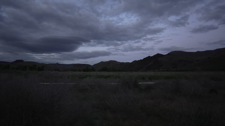 Time lapse of storm clouds rolling over hills at dusk in Oregon