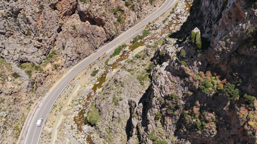 Aerial drone view of a road winding through a deep rocky canyon, Kourtaliotiko Gorge, Greece